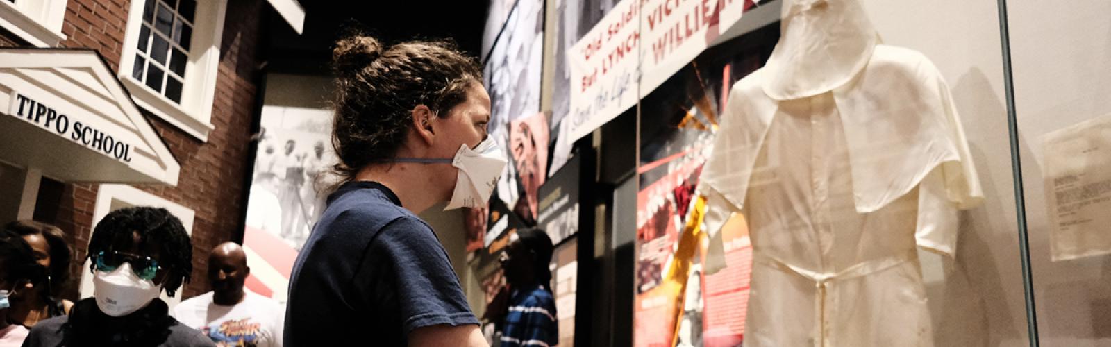 Woman examining KKK uniform on display at exhibit at Civil Rights Tour