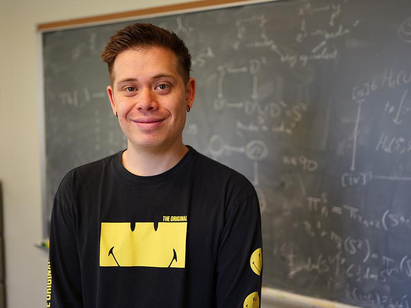 JD Quigley in front of blackboard